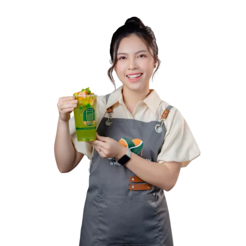 Giảng viên Ly Phạm mặc tạp dề Saly Academy, cầm ly đồ uống thành phẩm